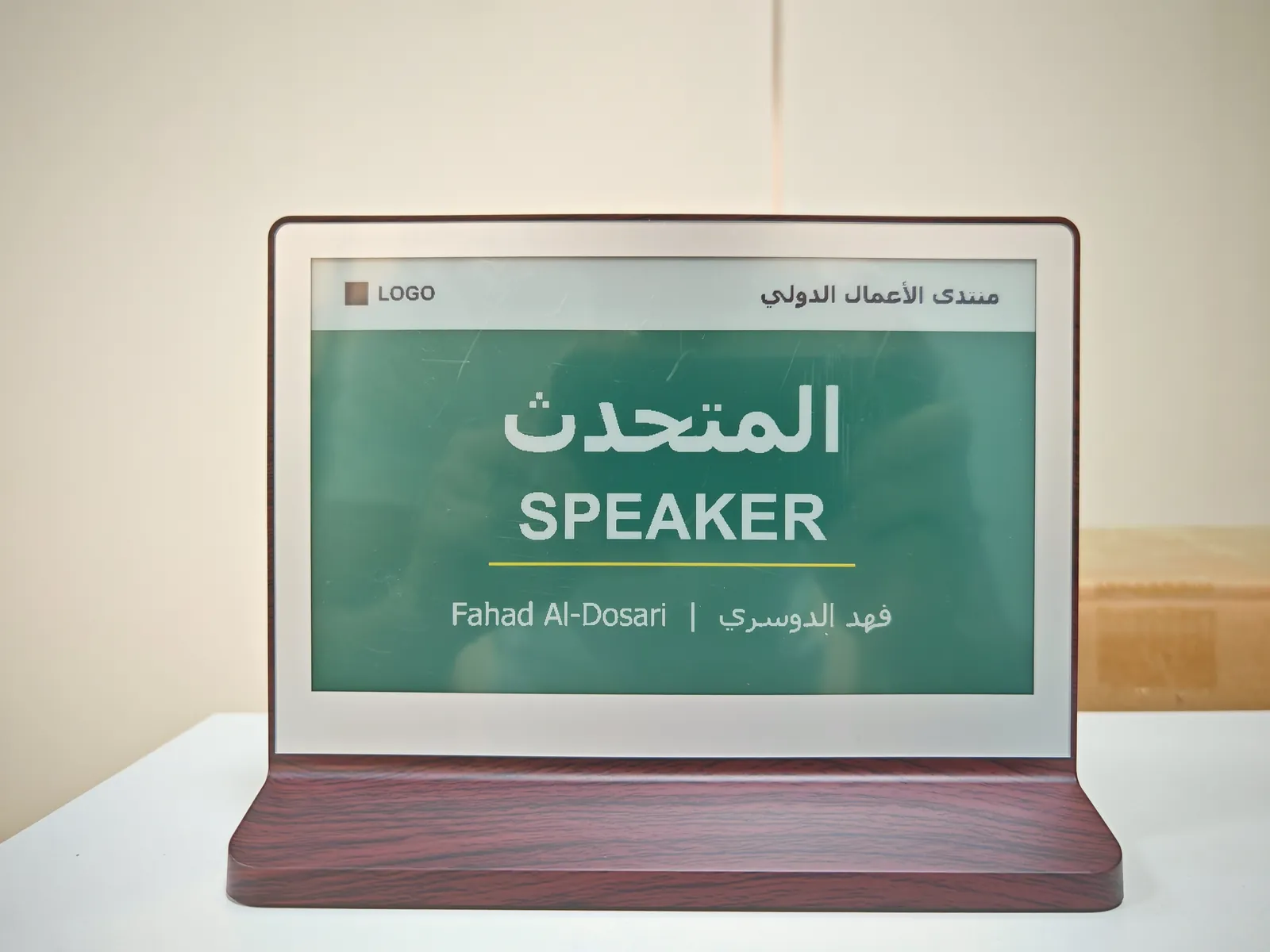 Canvas Desk Sign 7.3 · 6-Color: Woodgrain base, bilingual speaker card in green and white.